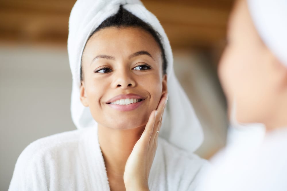 Woman admiring smoother, glowing skin in the mirror after laser skin rejuvenation treatment at a facial aesthetics clinic