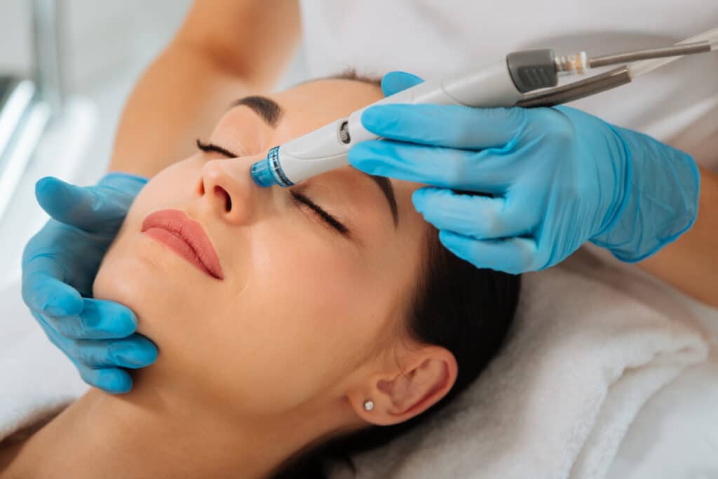 Woman receiving a HydraFacial treatment for smoother, glowing skin. Woman receiving a HydraFacial treatment for smoother, glowing skin.